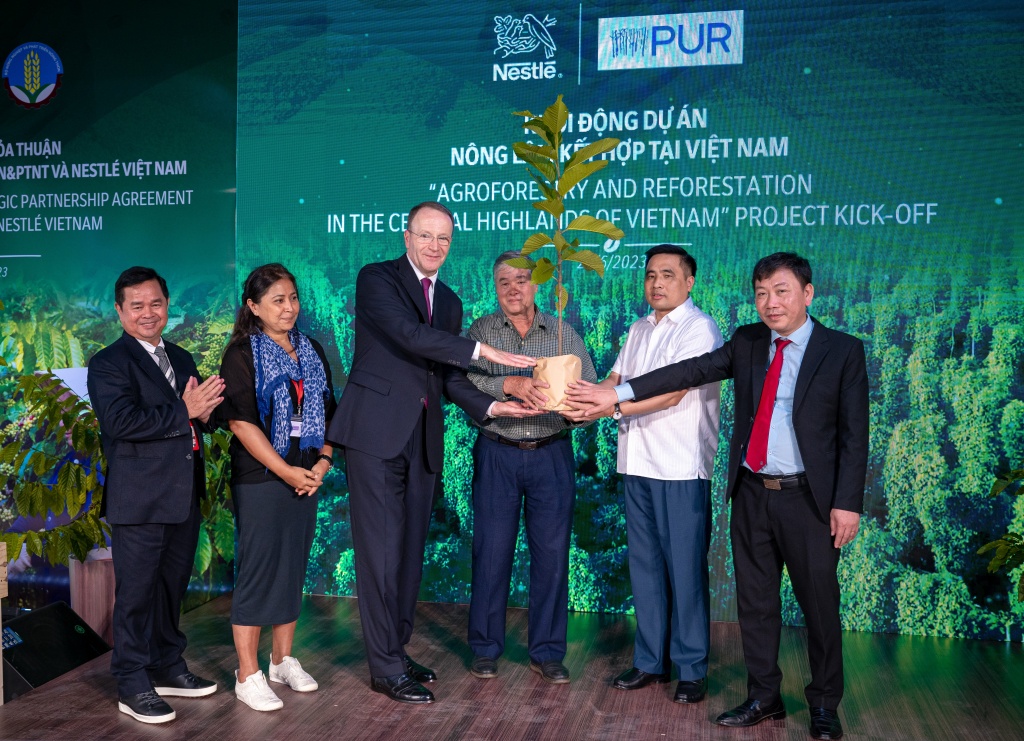 Ông Mark Schneider, Giám đốc điều hành Tập đoàn Nestlé (thứ 3 từ trái sang) trao cây đến người nông dân (thứ 4 từ trái sang), khởi động dự án Nông lâm kết hợp tại Việt Nam.. 