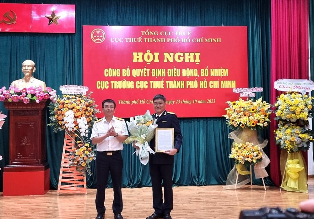 Tổng cục trưởng Tổng Cục Thuế Mai Xuân Thành trao quyết định và hoa chúc mừng ông Nguyễn Nam Bình (phải). Ảnh: CTV