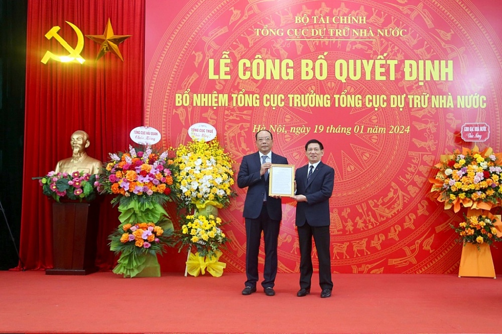 Bộ trưởng Bộ Tài chính Hồ Đức Phớc (bên phải) trao quyết định và tặng hoa ông Vũ Xuân Bách, tân Tổng cục trưởng Tổng cục Dự trữ Nhà nước. 