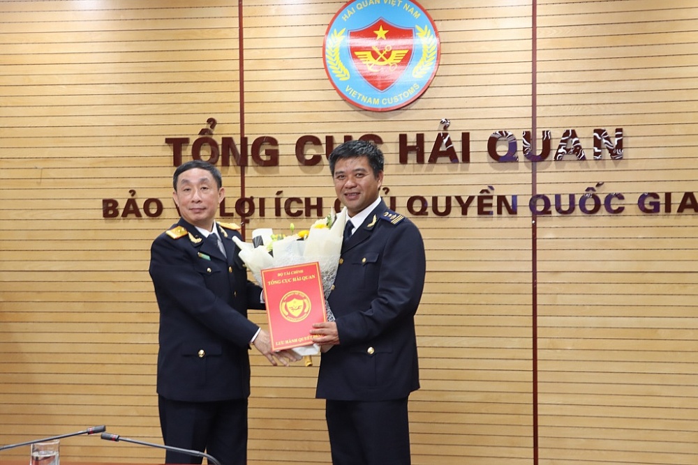 Phó Tổng cục trưởng Tổng cục Hải quan Hoàng Việt Cường (bên trái) tăng hoa chúc mừng và trao quyết định cho ông Đặng Thanh Dũng. Ảnh: Q.H