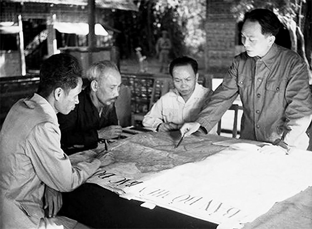 Đại tướng Võ Nguyên Giáp (đứng bên phải) trình bày với Chủ tịch Hồ Chí Minh và các đồng chí lãnh đạo Đảng, Nhà nước kế hoạch mở chiến dịch Điện Biên Phủ năm 1954. 	Ảnh: TL