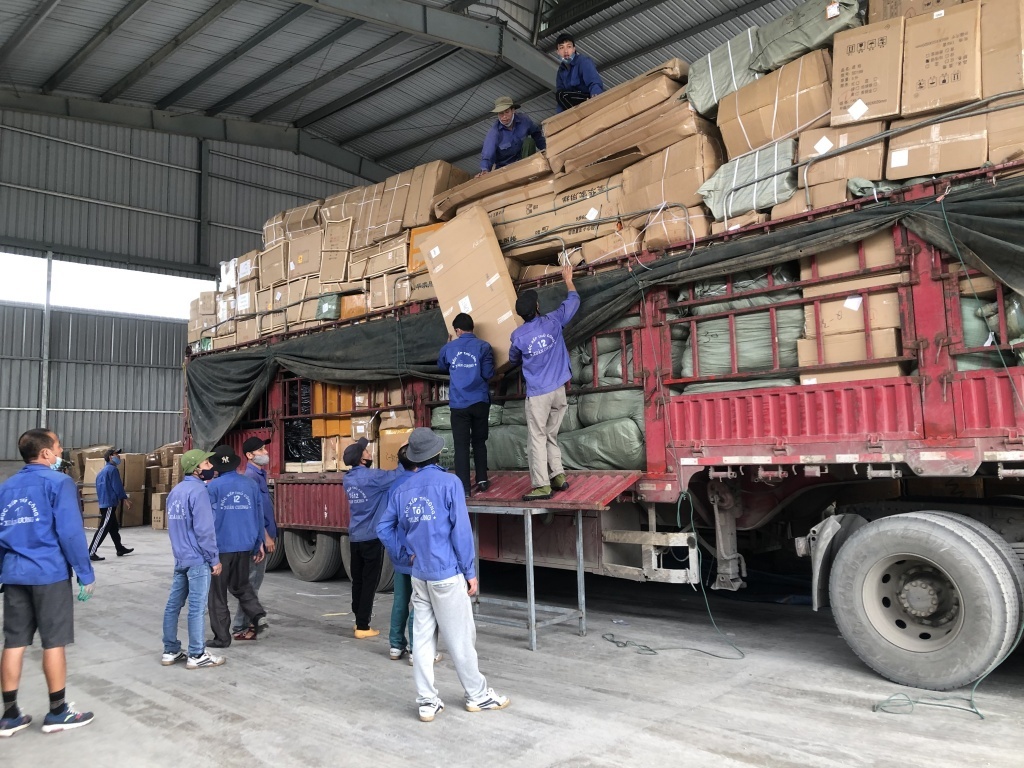 Công nhân tháo dỡ sang tải hàng gửi qua dịch vụ bưu chính, chuyển phát nhanh tại cửa khẩu quốc tế Hữu Nghị. 	Ảnh: H.Nụ