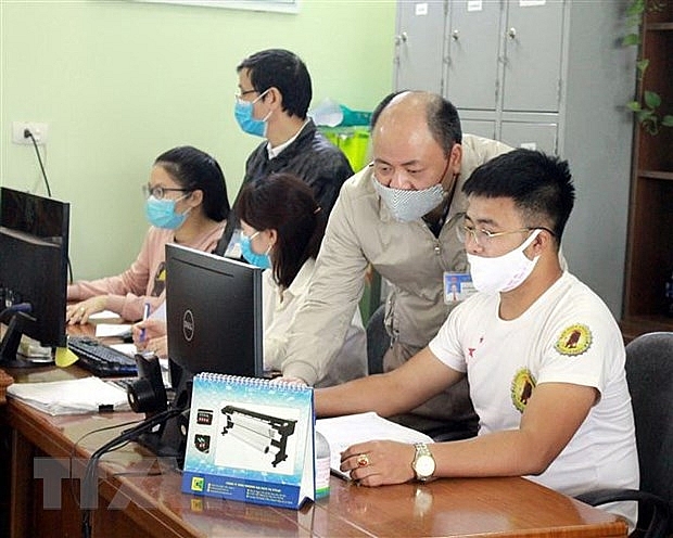 Cán bộ Chi cục Thuế ở Bắc Giang hướng dẫn nhân viên một công ty làm thủ tục gia hạn nộp thuế. 	 	Ảnh: Đồng Thúy/TTXVN