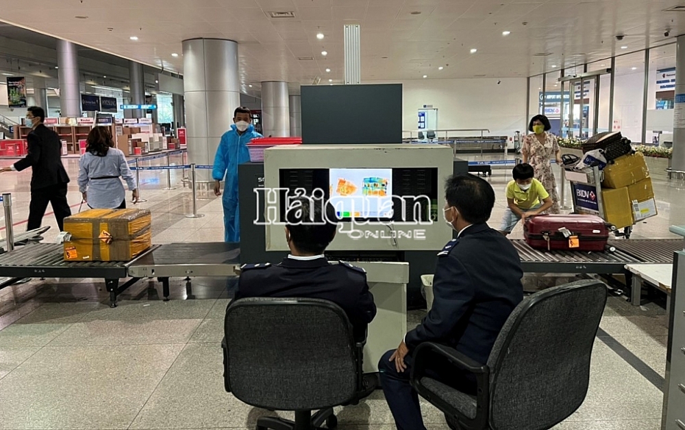 Công chức hải quan sân bay Tân Sơn Nhất soi chiếu hành lý cho hành khách nhập cảnh ngày 15/2/2022. Ảnh Nguyễn Khánh