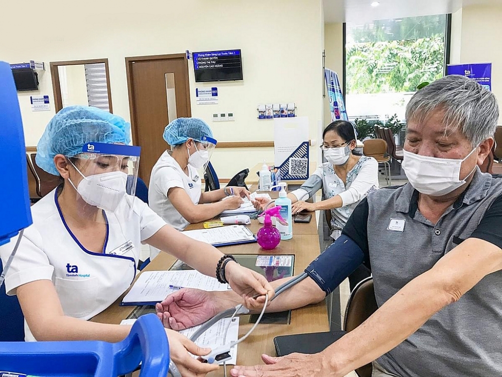 Điều dưỡng Bệnh viện đa khoa Tâm Anh đo huyết áp cho người bệnh trước khi tiêm. Ảnh Phong Lan