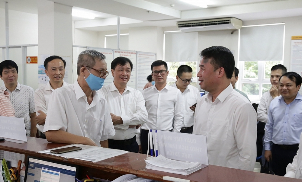 Tổng Giám đốc BHXH Việt Nam - ông Nguyễn Thế Mạnh trao đổi với người dân đến làm việc qua tính năng đặt lịch làm việc trực tuyến tại bộ phận Một cửa BHXH TP.HCM. 