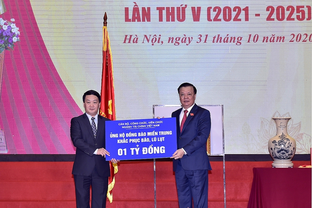 Bộ trưởng Đinh Tiến Dũng (phải) trao tiền ủng hộ tới đại diện Ủy ban Trương ương Mặt trận tổ quốc Việt Nam.